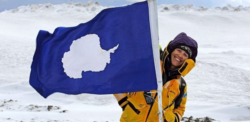 An expedition leader poses with an Antarctic flaf