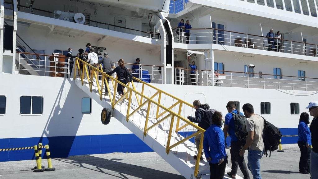 Passengers walk up the gangway of an expedition cruise ship at the dock in Puerto Madryn, bound for South Georgia and Antarctica