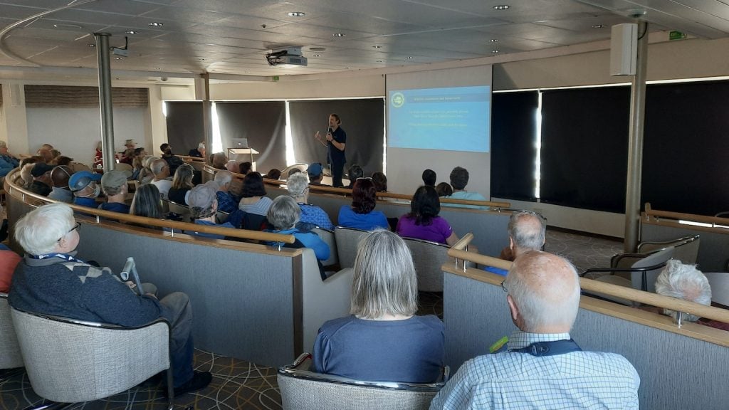 An expedition guide gives a talk in the lecture theatre on board an Antarctic cruise ship.