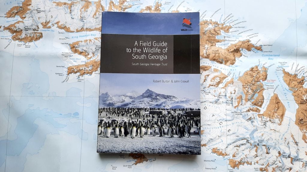 A copy of the book 'A Field Guide to the Wildlife of South Georgia' by Robert Burton and John Croxall (South Georgia Heritage Trust), sitting on a map of South Georgia