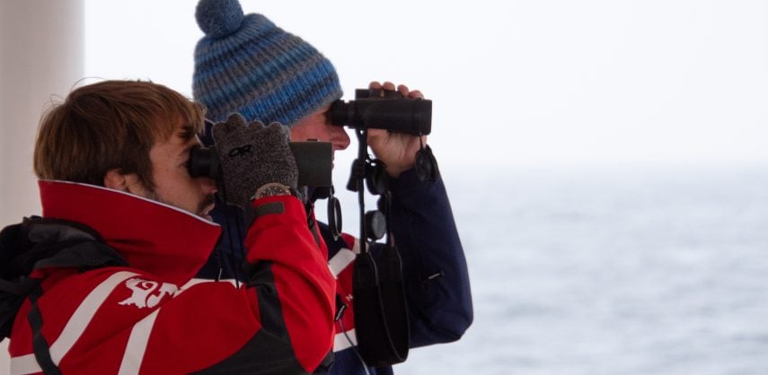 Two polar tourists with binoculars