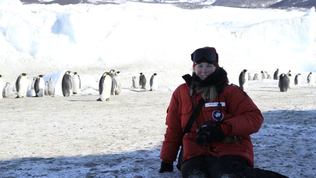 Female scientist on the Antarctic ice with emperor penguins