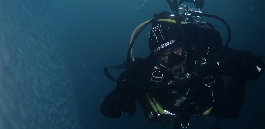 Barrington 'BJ' Scott swimming along an ice wall in Antarctica in scuba gear